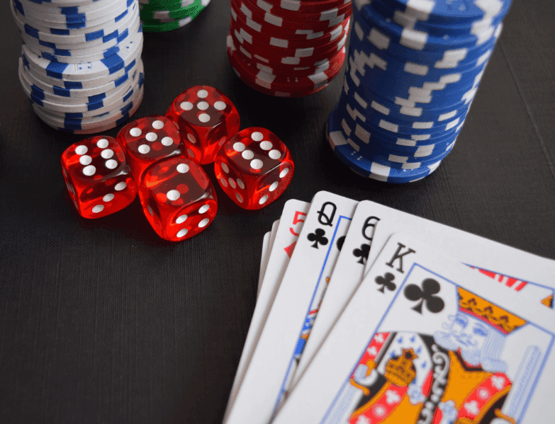 A deck of cards, stacks of poker chips and some dice on a table.