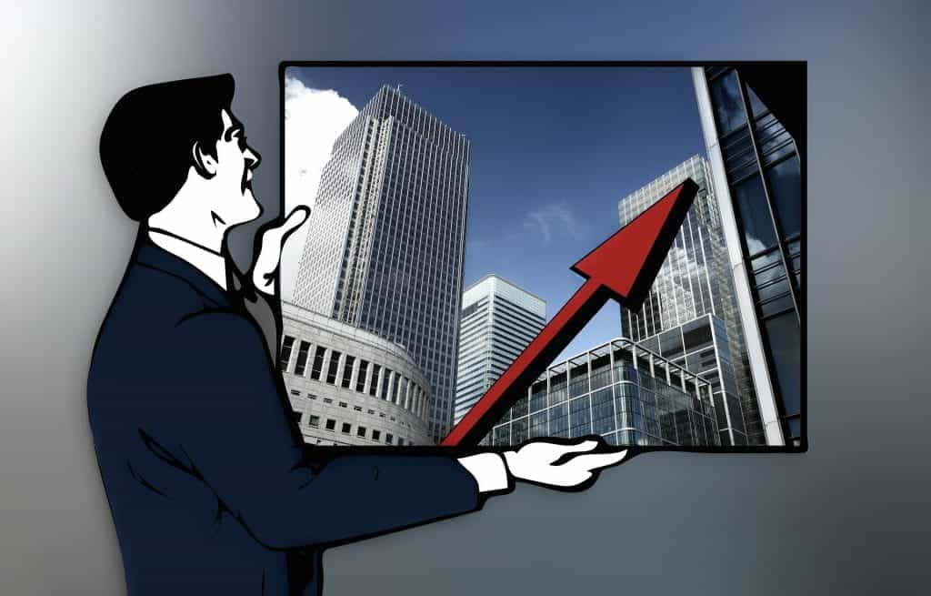 A graphic of a man in a suit holding a large photograph of skyscrapers. Superimposed over the skyscrapers is a large red arrow pointing up. 