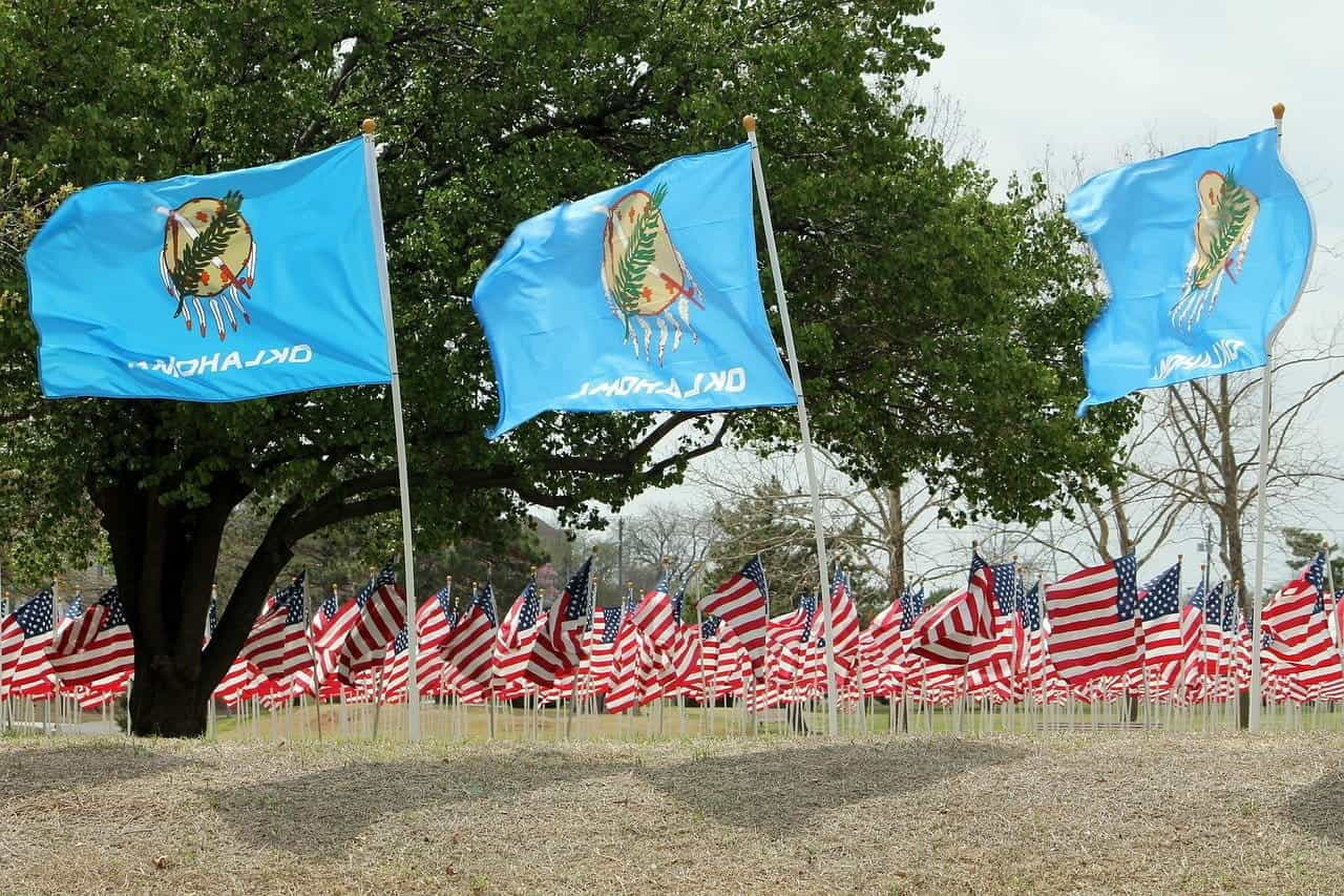 Rows of American flags with waving Oklahoma state flags in front.