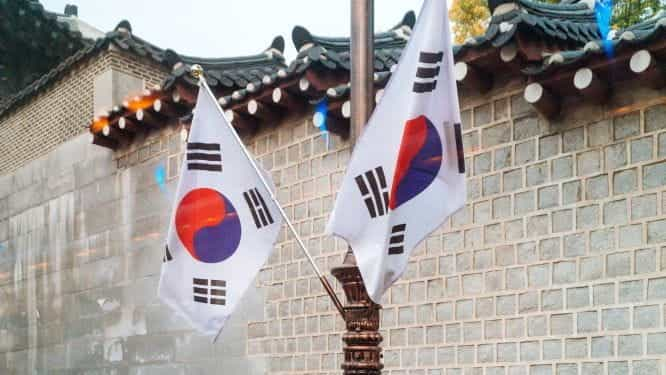 South Korea flags next to a traditional building.