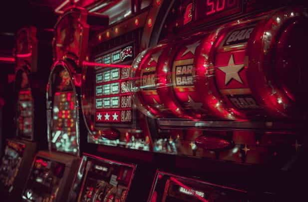 A close-up view of a row of slot machines, glowing red neon lights.