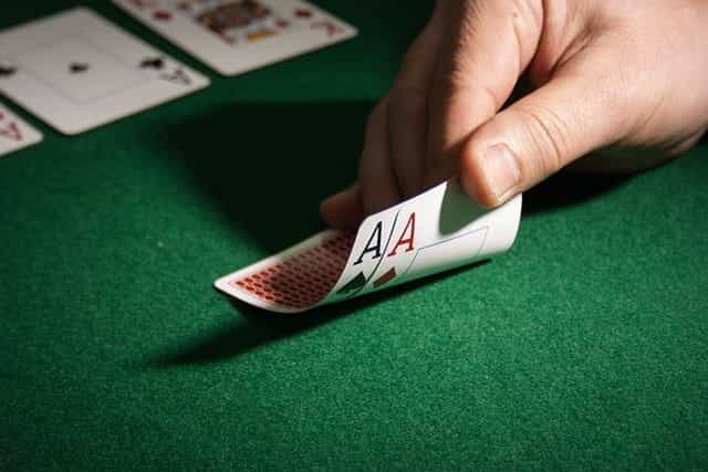 Two Ace cards lay face down with values revealed on poker table.