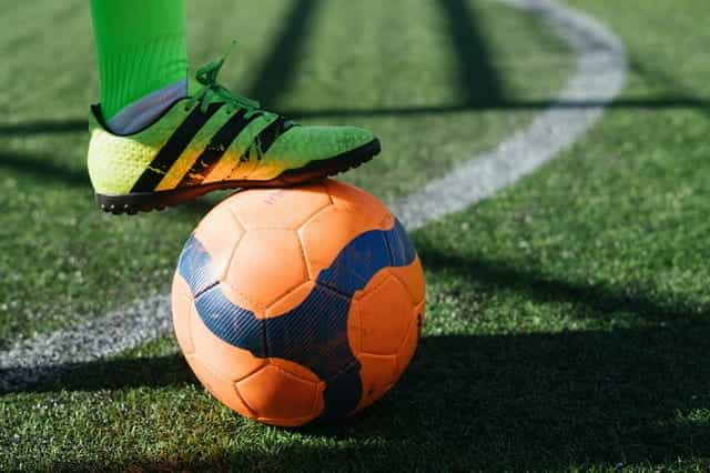 A footballer with foot on an orange football.