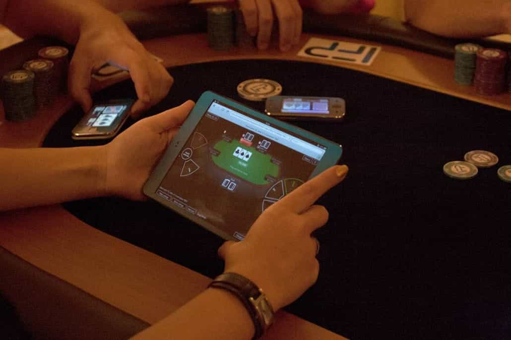 An individual plays online poker while sat at a traditional poker table.