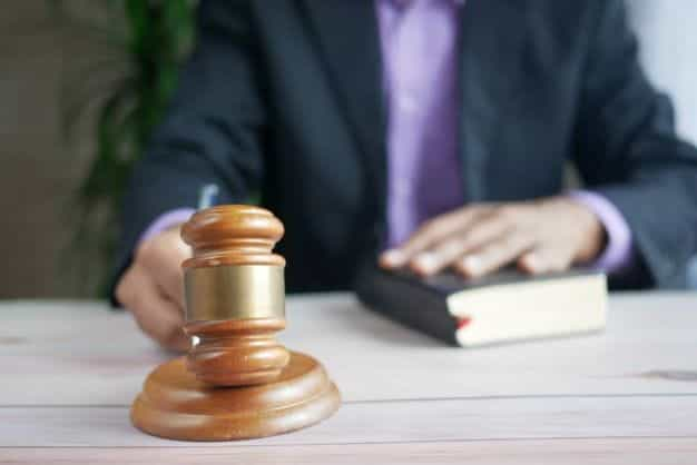 A man in a suit with a book and a gavel.