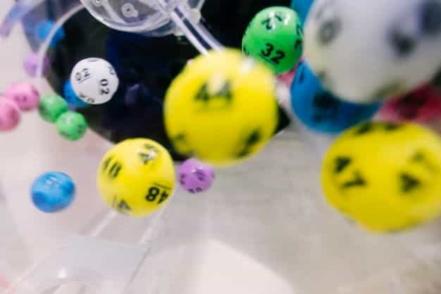 A mass of colorful lottery balls spin in a drum.