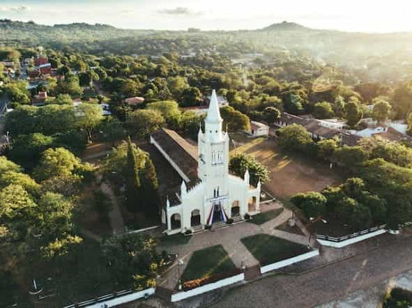 A church building surrounded by green trees in Paraguay.