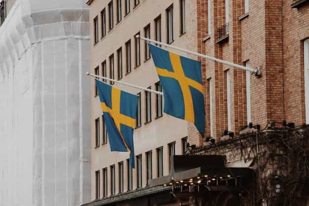 Two Sweden flags mounted on the front of a brick building.