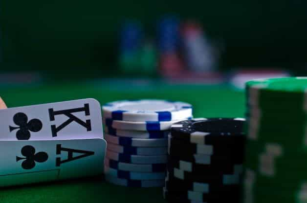 Suited Kings and Aces being looked at next to a stack of poker chips.