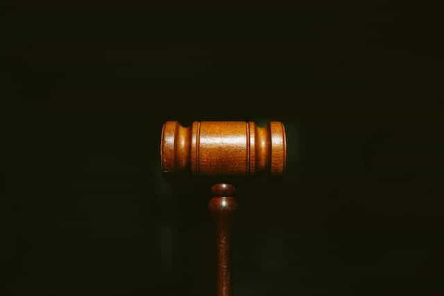 A wooden gavel sits on a black surface.