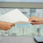 A person handing a document to another person.