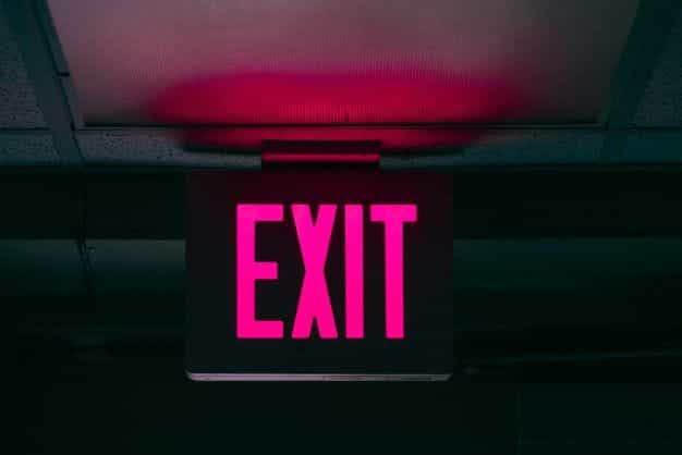 A neon pink exit sign against a dark backdrop.