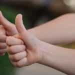 Two people’s hands giving the thumbs up sign in approval.