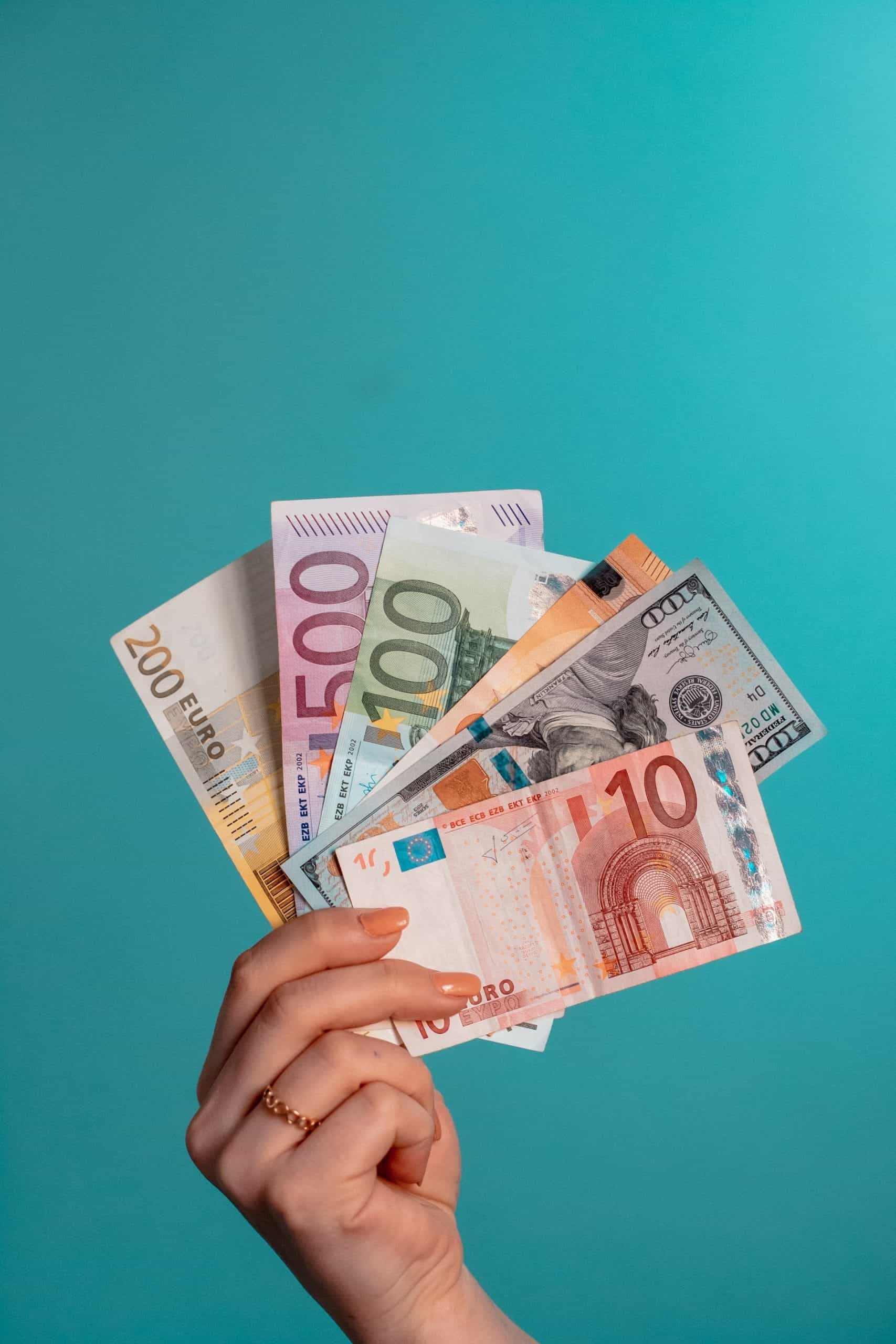 A woman’s hand holding up multiple denominations of euros.