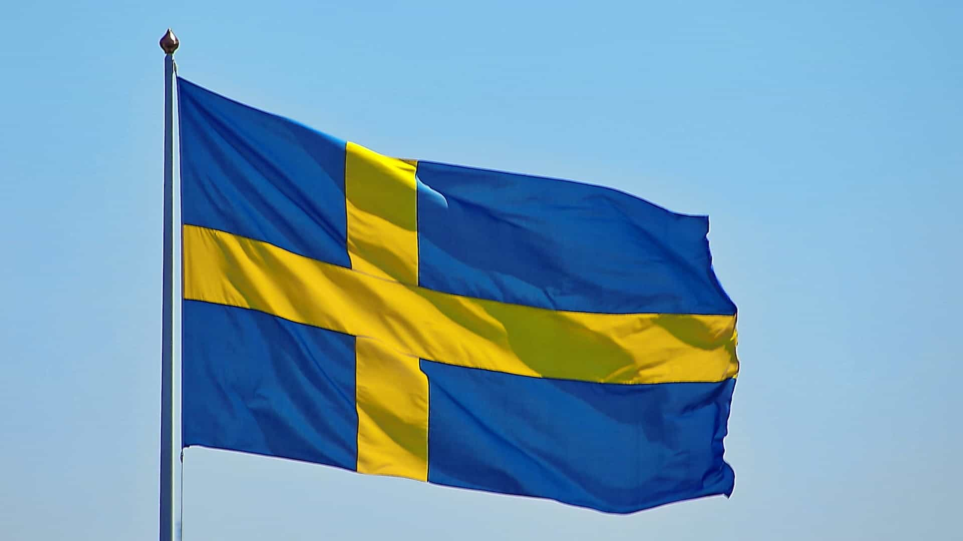 The Swedish flag fluttering against a blue sky.