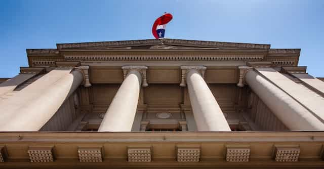 The Chilean flag waves over a government building with a facade of large columns.