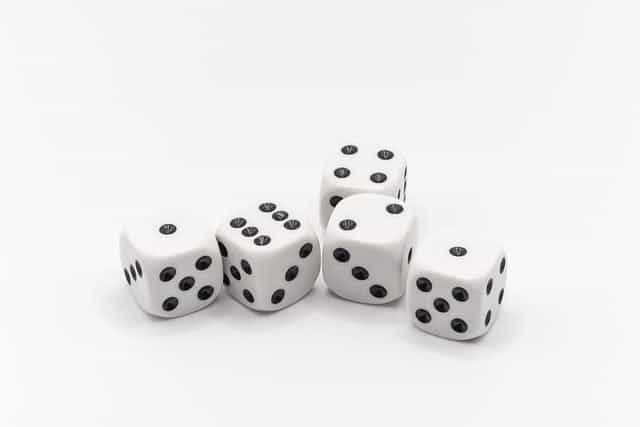 Five die placed next to each other on a white background with different number faces showing.