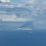 A cloudy ocean shore from the sea reveals the Rock of Gibraltar.