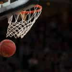 A basketball swishing through the net of a hoop during a game as a result of a player throwing it in and scoring a point.