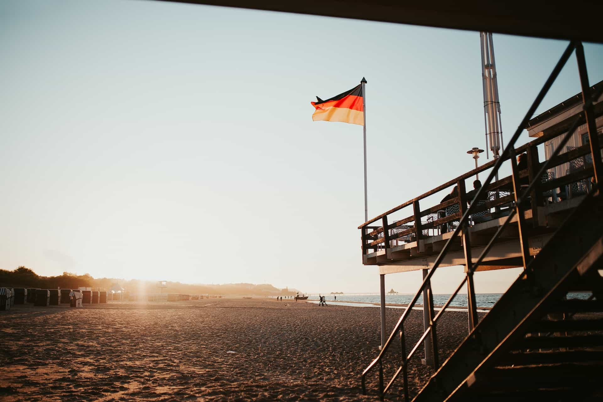 A black, red, and yellow flag on a structure at a beach.