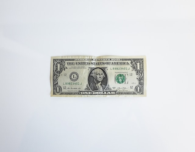 A US Dollar bill lying flat on a white surface, prominently displaying the face of former US President George Washington.