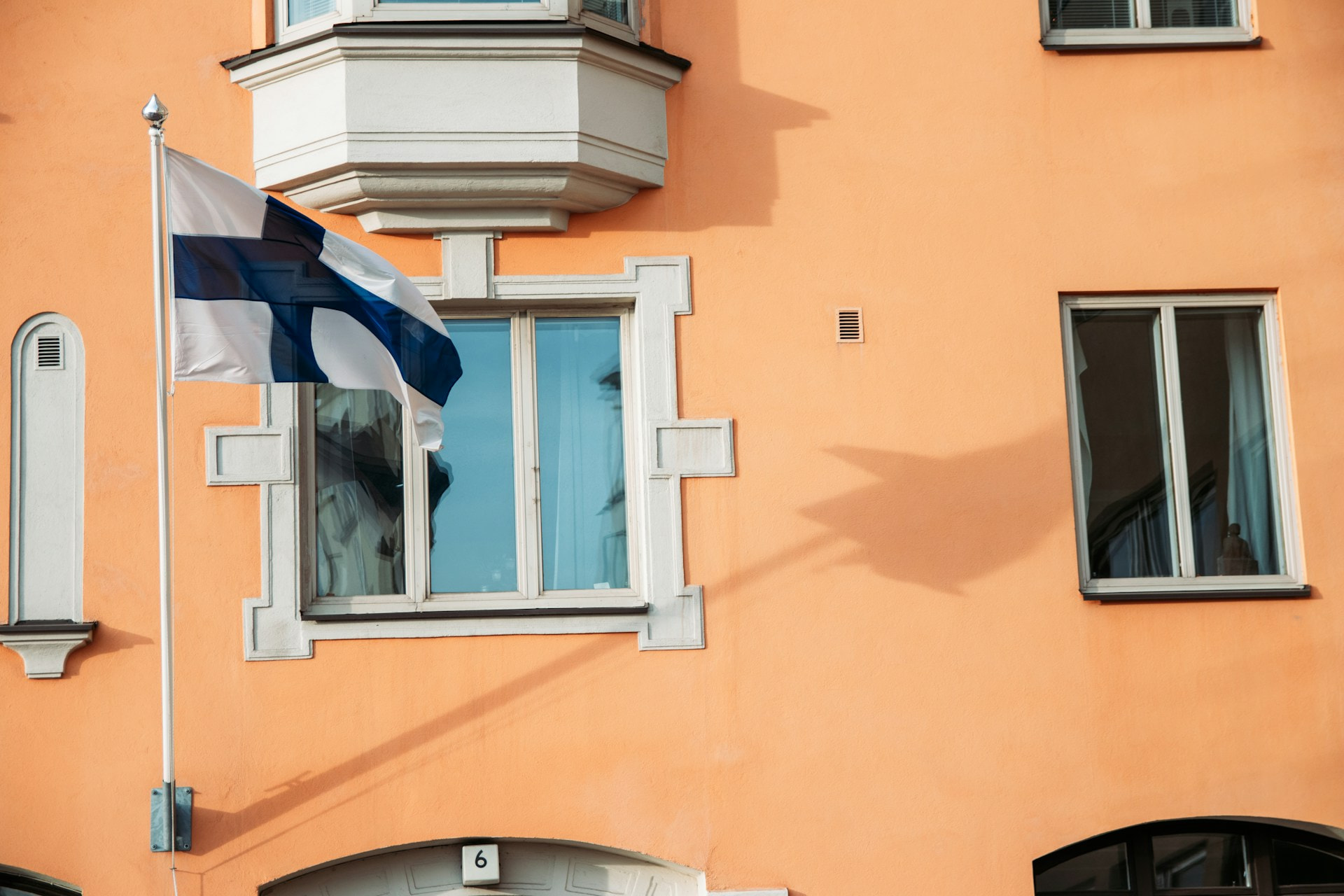 A white and blue flag in front of a window of a brown building.