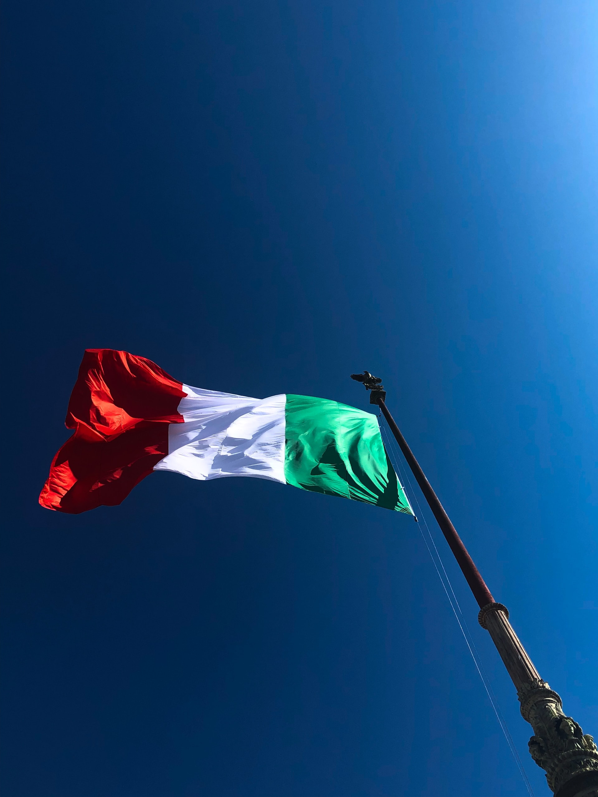 A red, white, and green flag against a blue sky.