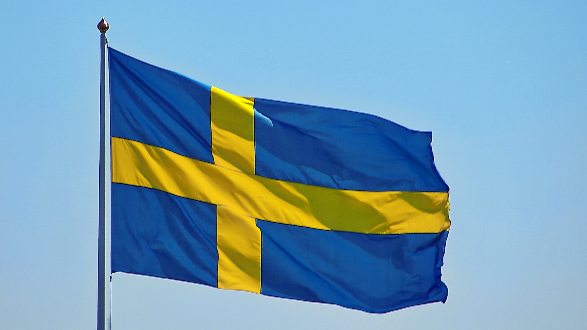 An unfurled flag in the wind against a blue sky.