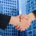 A handshake between two businesspeople on a blue background.