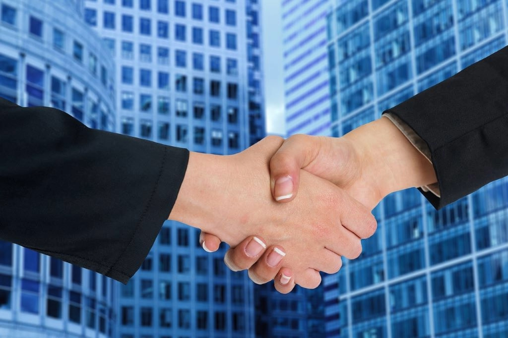 A handshake between two businesspeople on a blue background.